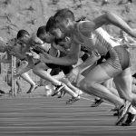 athletes running on track and field oval in grayscale photography